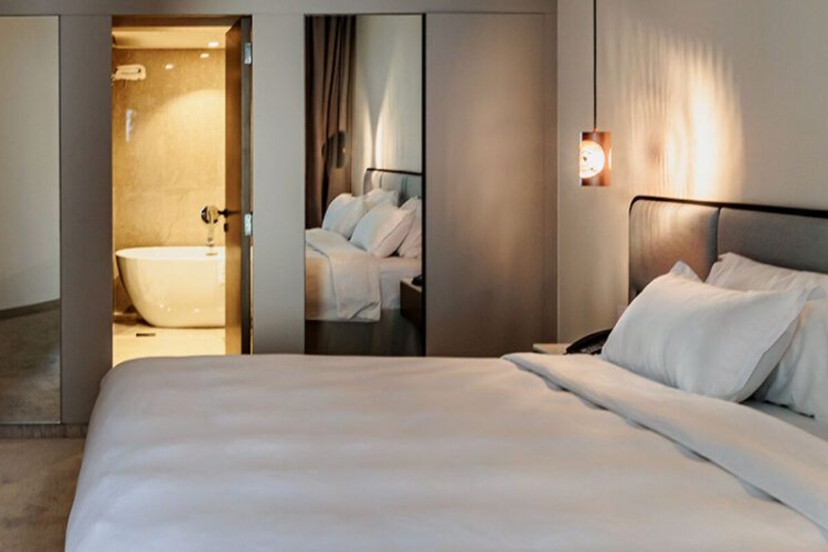 Une chambre d’hôtel avec un grand lit, une télévision, une salle de bain avec baignoire et un miroir.