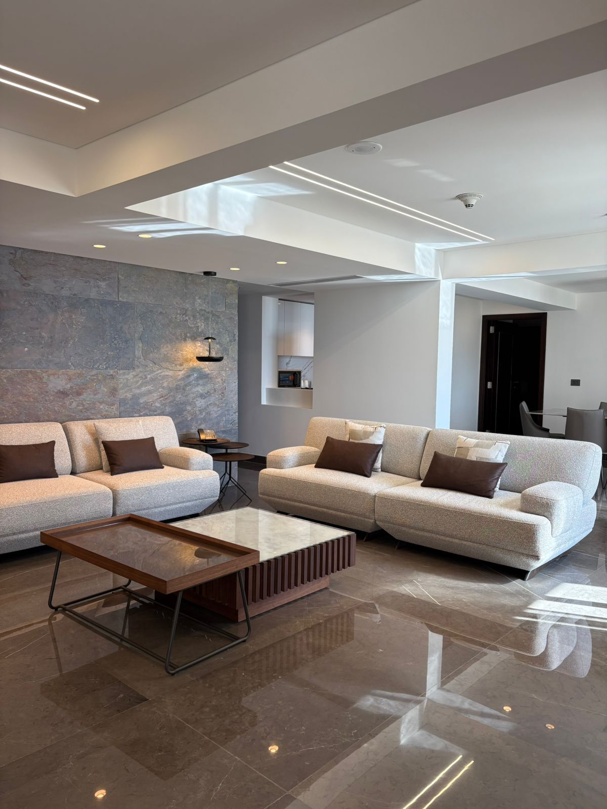Una sala moderna con un sofá modular, una mesa de centro y una pared de acento de piedra.