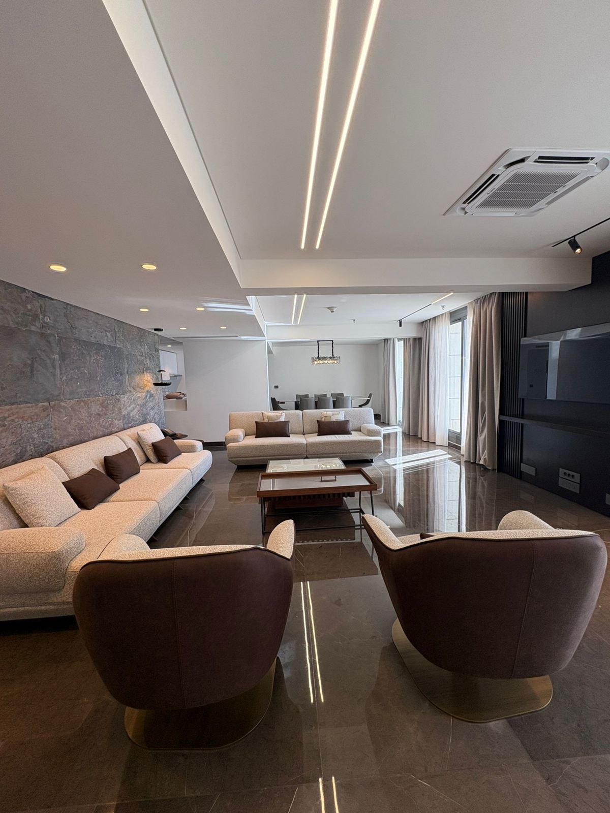 Una sala de estar moderna con un sofá, sillones, una mesa de centro y una chimenea.