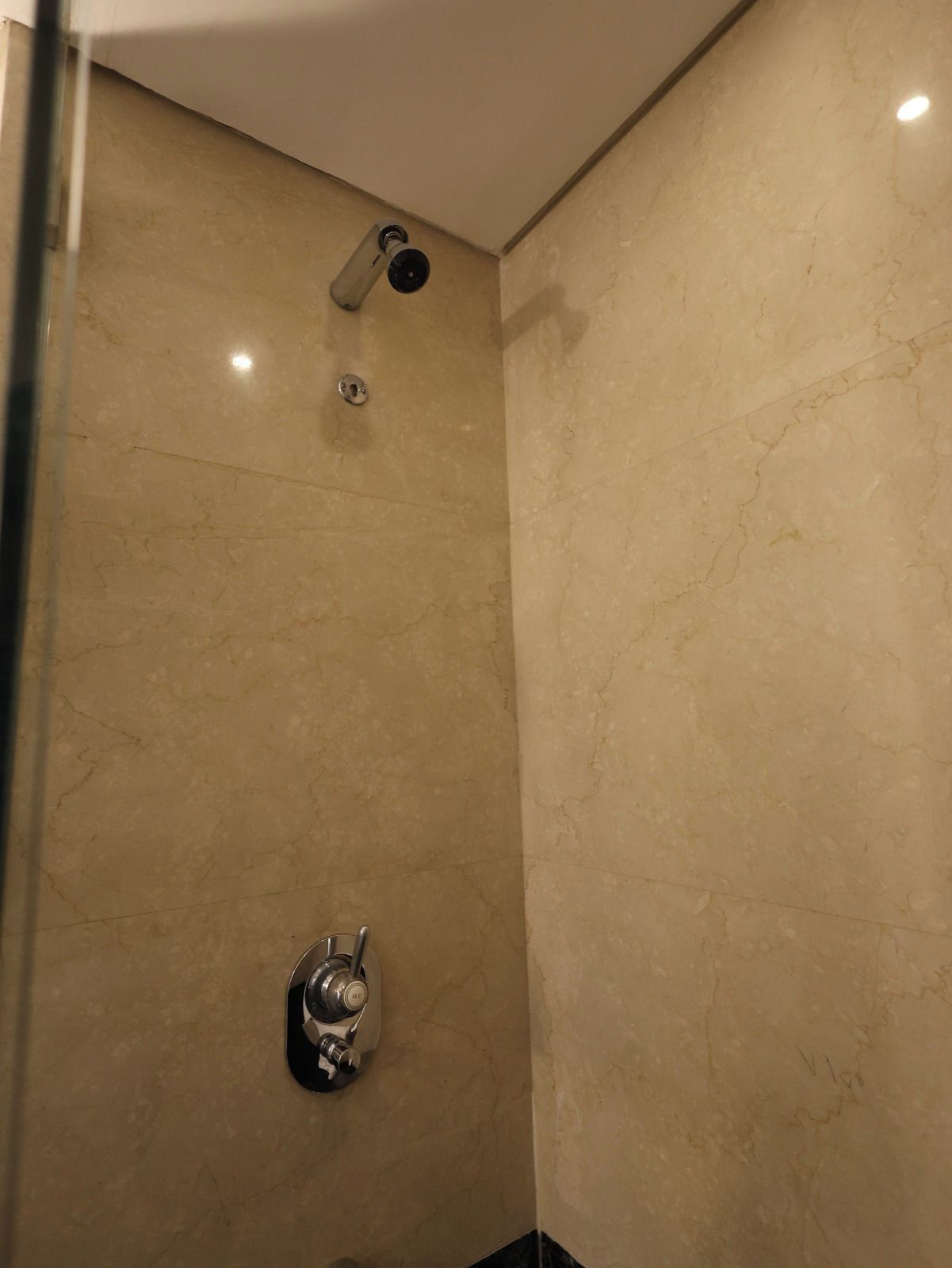 Un área de ducha con un cabezal de ducha de mano y una llave de control de pared.