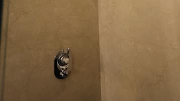 Un área de ducha con un cabezal de ducha de mano y una llave de control de pared.