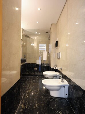 Une salle de bain moderne dotée d’une douche à parois de verre, de toilettes et d’un bidet.