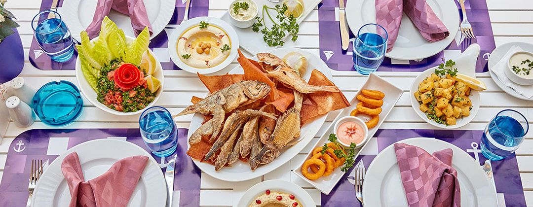 Una mesa dispuesta con diversos platos, bebidas y cubiertos, indicando una preparación para comer.