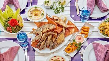 Una mesa dispuesta con diversos platos, bebidas y cubiertos, indicando una preparación para comer.