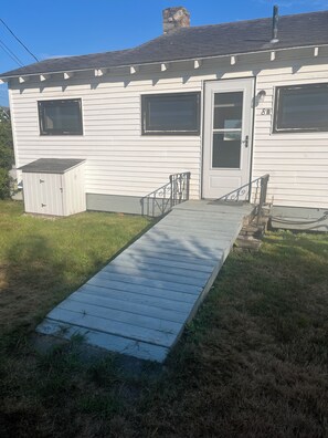 A single-story house with a front porch, a garage door, and a small shed. - Waterfront peaceful 2-bedroom cottage in charming Freeport perfect for relaxing (Freeport)