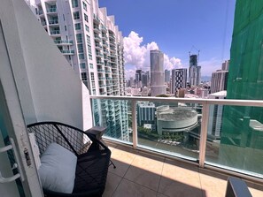 Uma varanda com vista para um horizonte urbano, incluindo edifícios altos e uma grua de construção.