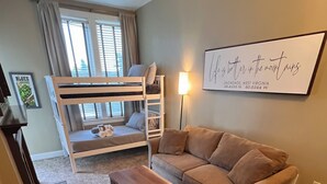 Ett rum med en våningssäng, en soffa, ett litet träbord och en vägglampa.