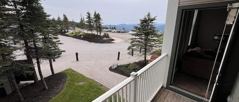 A balcony with a view of a paved area with trees and a distant mountain range.