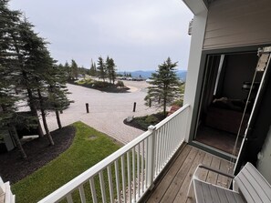 Ein Balkon mit Blick auf eine gepflasterte Fläche mit Bäumen und einem entfernten Gebirge.