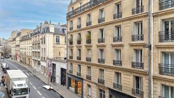 Gadesyn af en parisisk bygning med flere etager, altaner og butiksvindue.