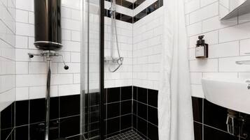 A modern bathroom with a black and white tiled design, a glass shower enclosure, and a white sink.
