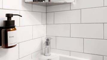 Un baño moderno con un lavamanos blanco, un dispensador de jabón y un espejo.