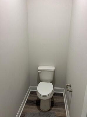 Un lavabo petit i de color blanc en un bany estret amb terra de fusta i un faldell gris.