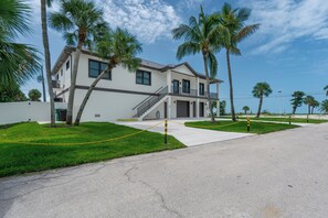 A two-story residential building with a balcony, surrounded by palm trees and a clear sky. - 🌴Seaside Cottage | Steps to the Beach 🏖️ Gulf Sunsets & Island Bliss 🌅 (Fort Myers Beach)