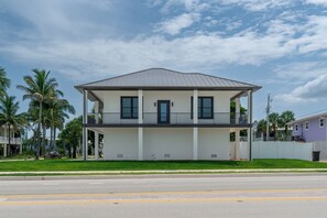 A two-story building with a flat roof, a balcony on the second floor, and a front porch. - 🌴Seaside Cottage | Steps to the Beach 🏖️ Gulf Sunsets & Island Bliss 🌅 (Fort Myers Beach)