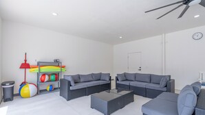Ein geräumiger Wohnbereich mit zwei grauen Sofas, einem Couchtisch und einem Deckenventilator.