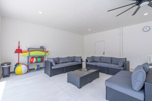 A spacious living area with two grey sofas, a coffee table, and a ceiling fan. - 🌴Seaside Cottage | Steps to the Beach 🏖️ Gulf Sunsets & Island Bliss 🌅 (Fort Myers Beach)