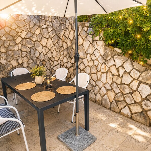 Eine Terrasse im Freien mit Steinmauer, Tisch und Stühlen sowie einer hängenden Leuchte.