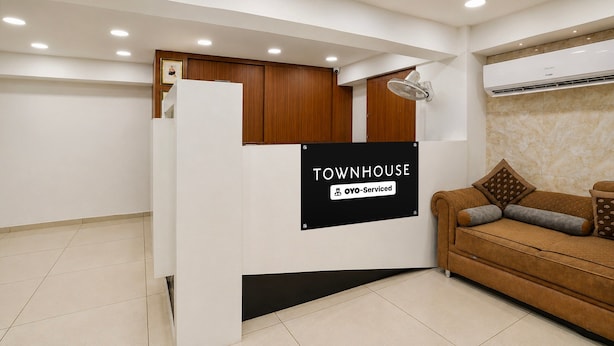 A reception area with a sign reading 'TOWNHOUSE OYO-Serviced,' a sofa, and a ceiling with recessed lighting. - Classic Simran Raghuveer Para (Rajkot)