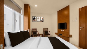 A hotel room with a large bed, two chairs, a TV, and artwork on the wall. - Classic Simran Raghuveer Para (Rajkot)