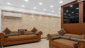 Two brown leather sofas with cushions, a wall-mounted air conditioner, and a sign indicating an office. - Classic Simran Raghuveer Para (Rajkot)