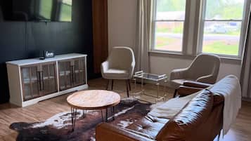 Sala de estar com sofá de couro, mesa de centro redonda, armário e ventilador de teto.
