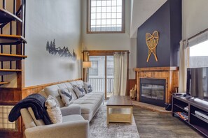 A living room with a sofa, coffee table, fireplace, and a bookshelf. - Sunset facing slopeside condo and pet friendly! (Snowshoe)