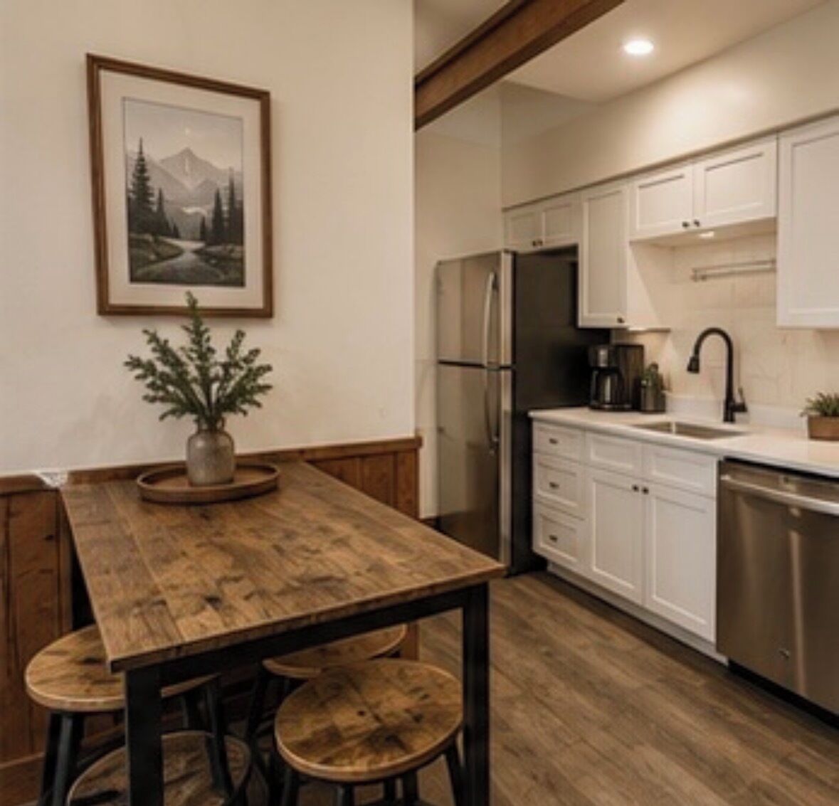 A kitchen with white cabinets, a stainless steel refrigerator, a coffee maker, and a potted plant.