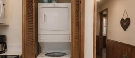 A compact laundry room with a washing machine and dryer, wooden cabinets, and a heart-shaped decoration on the wall.