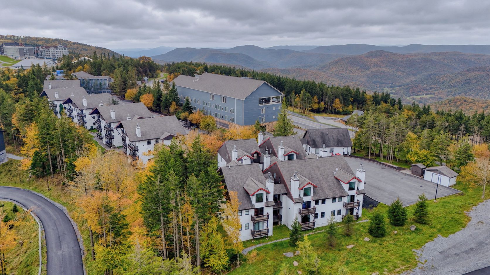 Un quartier résidentiel comprenant plusieurs maisons, un grand immeuble et une route sinueuse.