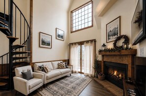 Ein Wohnzimmer mit Kamin, einer Couch, einem Teppich mit Muster und einer Treppe.