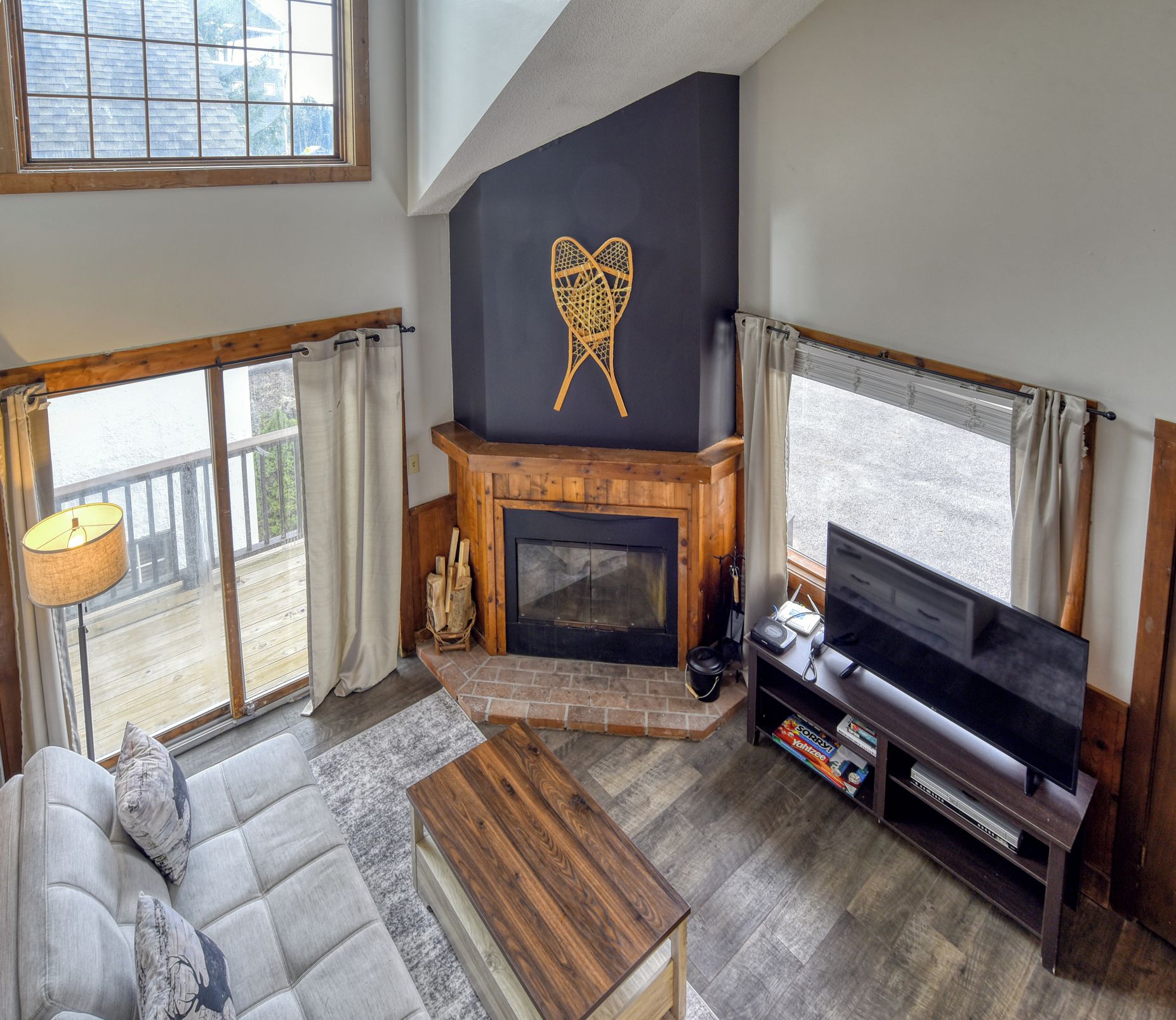 A living room with a fireplace, a sofa, a TV, and a large window.