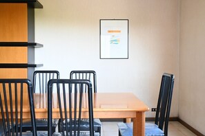 Ein Zimmer mit einem Holztisch, vier schwarzen Stühlen, einem gerahmten Bild an der Wand und einem hellen Boden.