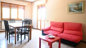 A room with a dining table, chairs, a red sofa, and a painting on the wall. - A50 - Massignano, spacious four-room apartment (Massignano)