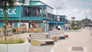 A modern building with a large sign reading 'STOCK' and a cafe named 'yolo' inside.