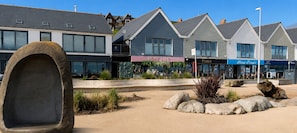 A row of modern buildings with commercial establishments, including a restaurant named 'Love Lily' and a shop called 'Coast'.