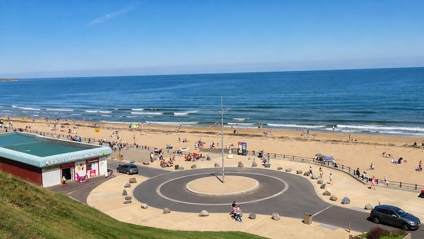 A coastal promenade with a roundabout, beach, and a building labeled 'Roker Amusements.'