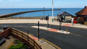 A coastal road with a pedestrian path, a small kiosk, and a view of the sea.