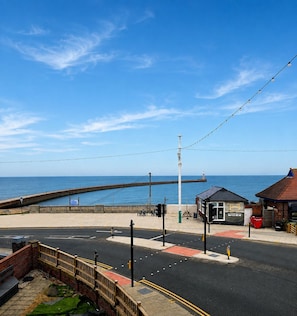 A coastal road with a pedestrian path, a small kiosk, and a view of the sea.