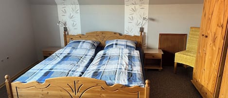 A bedroom with a wooden bed, two bedside tables, a chair, and a wardrobe.