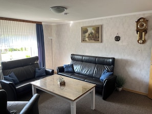 Ein Wohnzimmer mit einer Ledersofa, einem Holztisch und einem Gemälde an der Wand.