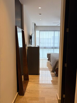 Ein Hotelzimmer mit einem Bett, einem Schreibtisch und einem großen Fenster mit Vorhängen.