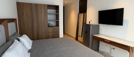A modern bedroom with a large bed, a ceiling fan, a TV, and a wooden wardrobe.