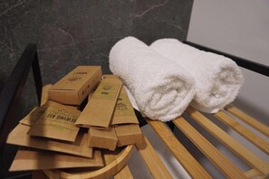 Eine hölzerne Bank mit zwei aufgerollten weißen Handtüchern und mehreren Kartons mit der Aufschrift 'SEMINING KIT' an einer Marmorwand.