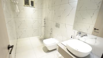 Un baño con inodoro blanco, lavamanos y zona de ducha.