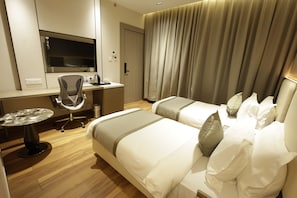 Habitación de hotel con escritorio, silla, dos camas y televisor.