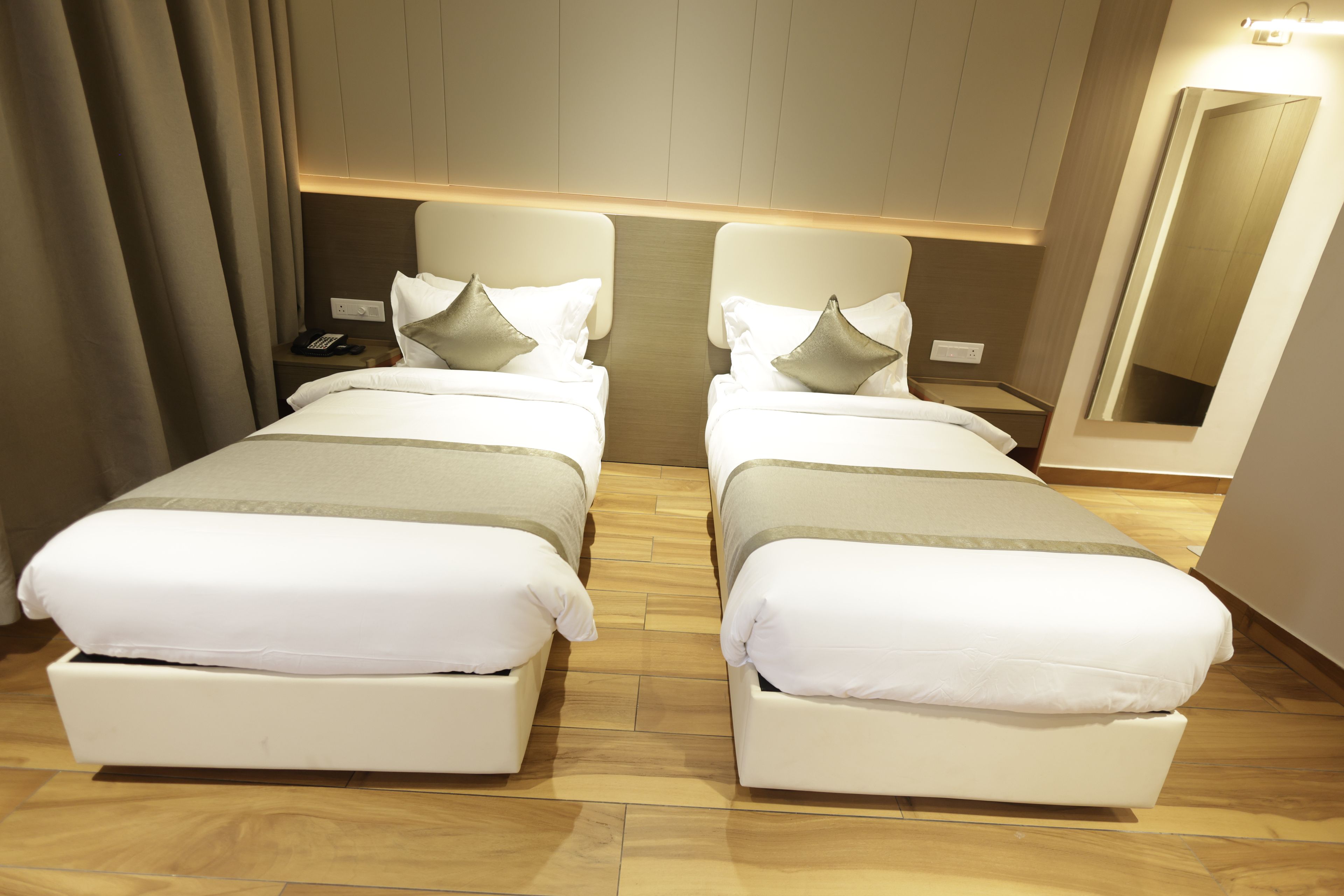 Un lit double avec une tête de lit en bois, une table de chevet avec un téléphone et un miroir au mur.