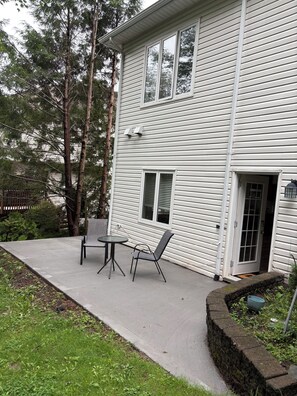 Une maison à deux étages avec un patio comprenant une table et deux chaises.