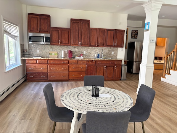 Una cocina moderna con armarios de madera, un refrigerador de acero inoxidable y un comedor con una mesa redonda y sillas.