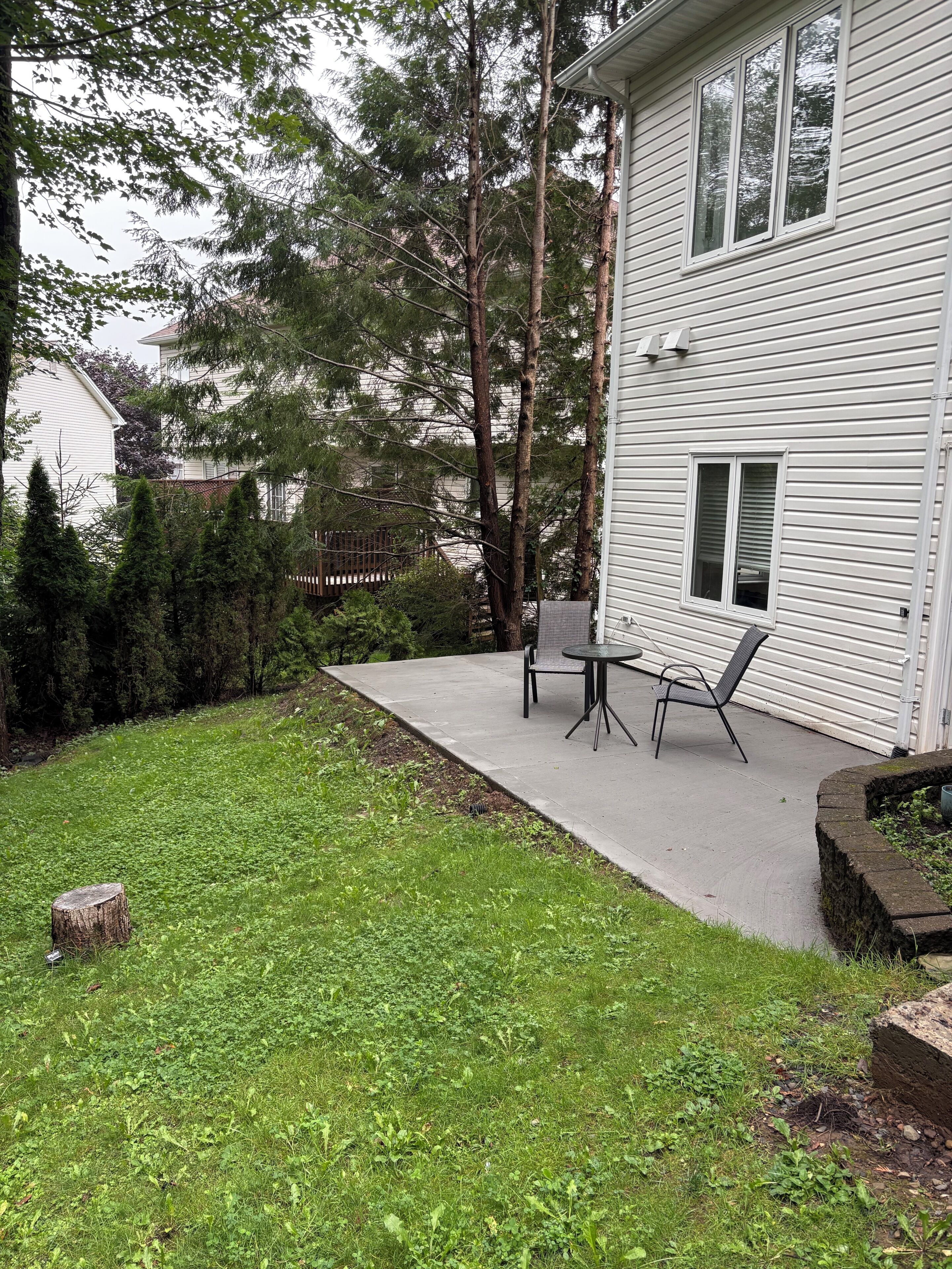 Il s’agit d’une propriété résidentielle dotée d’une terrasse, d’une petite table et de chaises, ainsi que d’un jardin avec de la pelouse et des arbres.
